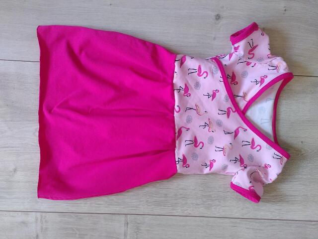 Rosa farbenes Kinderkleidchen mit Flamingos auf dem Oberteil und pinkem unifarbenem Rock.
