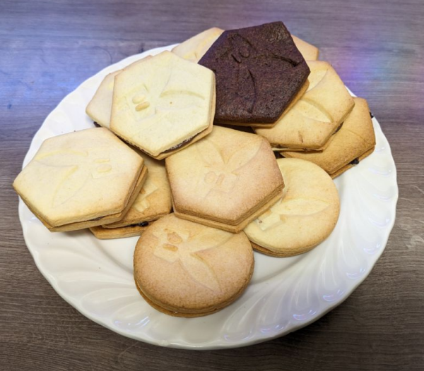 Ein Teller mit mehreren Keksen mit Logo des easterhegg 2024: Zwei Kekse sind mit einer Füllung zu einem Doppelkeks fusioniert, ein Keks ist schokoladig braun